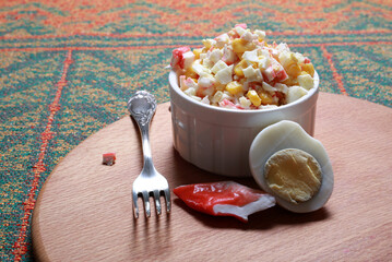 Salad with crab, egg and corn in a white bowl close-up