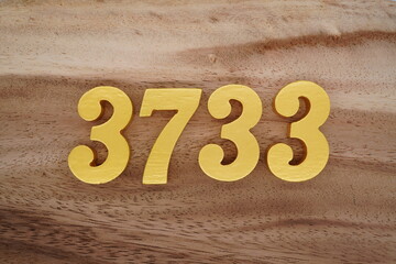 Golden Arabic numerals on a real brown and white wooden floor number 3733