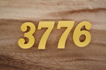 Golden Arabic numerals on a real brown and white wooden floor number 3776