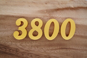 Golden Arabic numerals on a real brown and white wooden floor number 3800