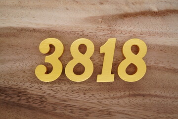 Golden Arabic numerals on a real brown and white wooden floor number 3818