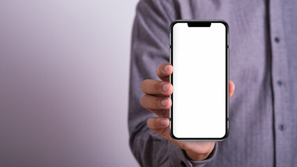 Close-up male hands holding smartphone white screen on gray empty space background. searching or social networks concept. online technology communication network.