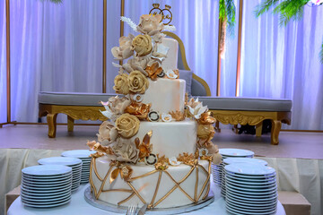 Golden wedding cake with golden roses and plates