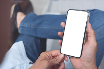Mockup cell phone. Man hand holding, using mobile relax on sofa at home. background empty space for advertise text