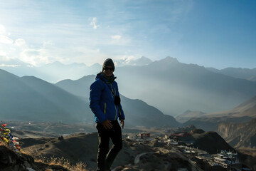 A man in hiking outfit standing on top of a mountain with the endless view on Himalayan chains....