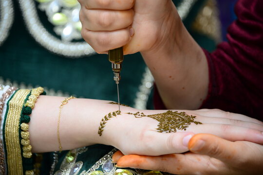 Artist applying henna tattoo on women hands. Mehndi is traditional moroccan decorative art. Close-up, top view.