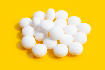 Naphthalene mothballs on yellow background.