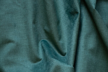 Dark green wrinkled fabric as a background close-up, fashion and trends, green