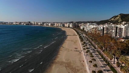 Fototapeta na wymiar Drone Shot of the Beach in a Bright Day with Trees and Blue Water