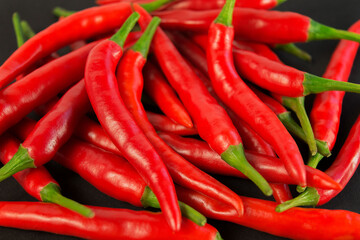 A group of spicy, fresh, red peppers. Hot hili on the black background. Close-Up