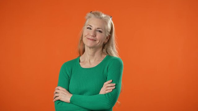 Portrait of blonde successful confident employee business mature woman 50s in green top shirt casual clothes look camera isolated on orange background copy space studio. Achievement career concept.