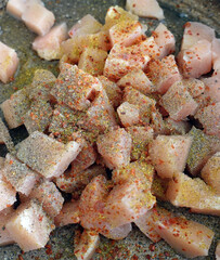 Chicken tenderloin cut into cubes in a pan, topped with pepper, salt, black pepper and dried thyme,