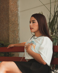 Cute red-haired girl with oriental features sitting on a bench