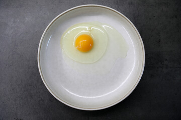 Raw egg in a plate on the kitchen table