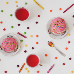 holiday, birthday party composition with colorful pink glazed donuts on white table, flatlay top view