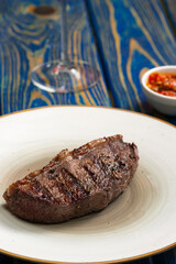 Fresh grilled meat.steaks with spices in white plate on blue wooden background