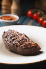 Roasted steak ,cherry tomatoes, salt and pepper on blue  wooden table.