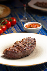 Roasted steak ,cherry tomatoes, salt and pepper on blue  wooden table.