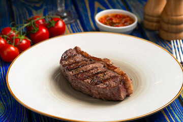 Roasted steak ,cherry tomatoes, salt and pepper on blue  wooden table.