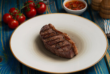 Grilled steak ,cherry tomatoes salt and pepper on wooden table.