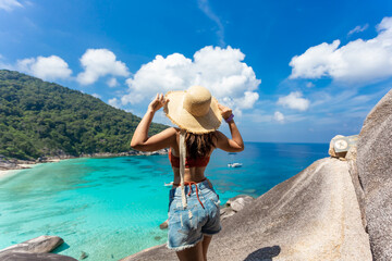 back view of women wearing a straw hat standing in view Beautiful sea and blue sky at Similan island, Phuket,Thailand.