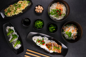 Various dishes of Asian cuisine with different types noodles and rice with shrimp, duck, vegetables and black sesame