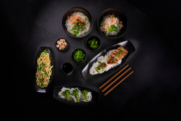 Various dishes of Asian cuisine with different types noodles and rice with shrimp, duck, vegetables and black sesame