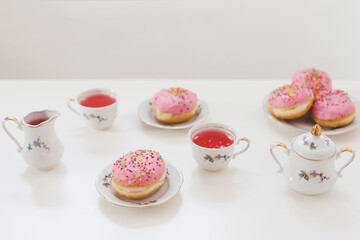 holiday, birthday party composition with colorful pink glazed donuts on white table, flatlay top view