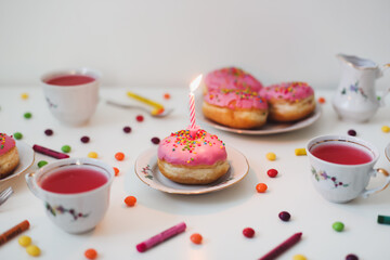 holiday, birthday party composition with colorful pink glazed donuts on white table, flatlay top view