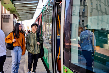 side view of young latin americans entering a tram. couple of musicians with instruments on their...
