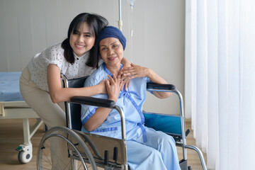 Cancer patient woman wearing head scarf and her supportive daughter in hospital, health and...