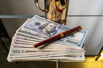 Various 100, 50, $20.5 US dollars, US banknotes, 100 dollars. With gold color mug and fountain pen.
