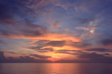 Naklejka na ściany i meble Morning sunrise from the sea in gray clouds