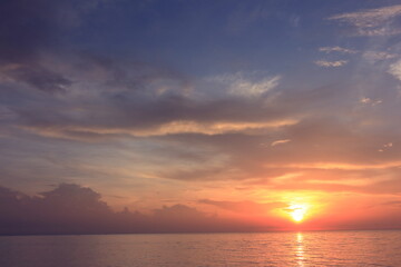 Morning sunrise from the sea in gray clouds