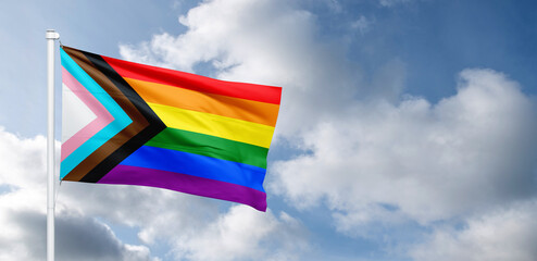 Progress LGBTQ rainbow flag waving in the wind at cloudy sky. Freedom and love concept. Pride...