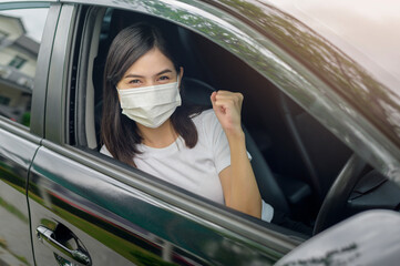 Young beautiful woman wearing a protective mask driving a car