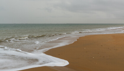 view of a beautiful and empty beach with shore break and golden sand