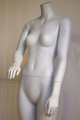 Naked female mannequin. Plastic dolls in store window display.