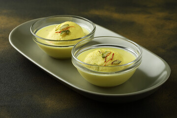 Rasmalai is an Indian dessert sweet with dry fruits and Saffron toppings, served in a bowl . selective focus