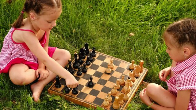 Little chess players have been playing every day since childhood to become chess champions. Children play board games on the grass on the lawn in the park