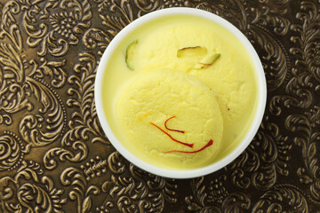 Rasmalai is an Indian dessert sweet with dry fruits and Saffron toppings, served in a bowl ....