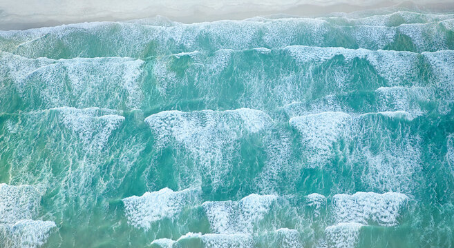 Ebb and flow of the sea. Aerial view of ocean waves moving toward the shoreline.