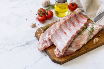 Raw veal calf brisket ribs meat with vegetable and spices on short spare rib for cooking on marble tabletop. Copy space.