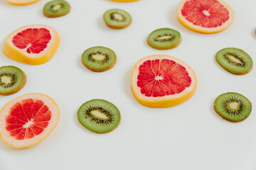 Fruity pattern of kiwi and grapefruit slices on the white background. Minimal colourful trend style