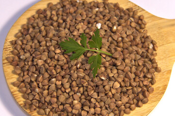 Buckwheat and greens in a wooden spatula. Close up. On a white background. Top view.