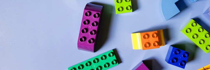 Colorful plastic building blocks flat lay on blue background. Child developing game. Pattern.children's bricks for construction. Building blocks background. Developing toys, copy space. web banner