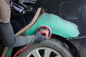 Grinding body parts with a pneumatic grinder before painting.