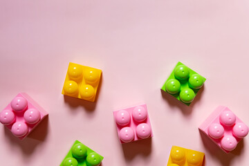 Colorful plastic building blocks flat lay. pink background. Child developing game. Pattern.children's bricks for construction. Building blocks background. Developing toys, copy space