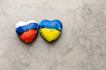 Obraz premium National flags of Ukraine and Russia of heart shape on grey marble background. Creative image about peace between Ukrainian and Russian people, talks, Negotiation.