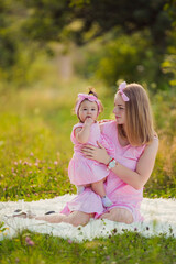 Fototapeta na wymiar mother and daughter in pink dresses sit on a white blanket
